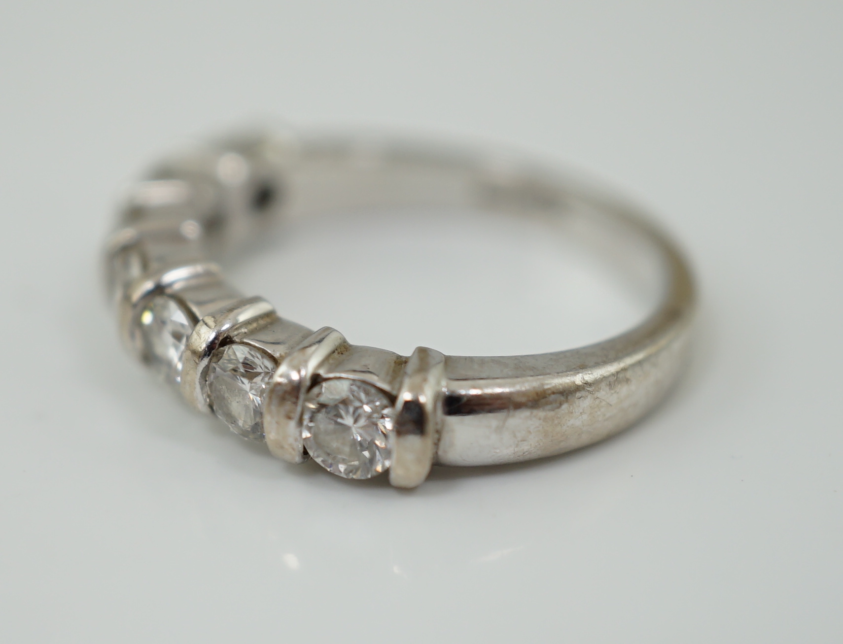 A modern 18ct white gold and seven stone round brilliant cut diamond set half hoop ring